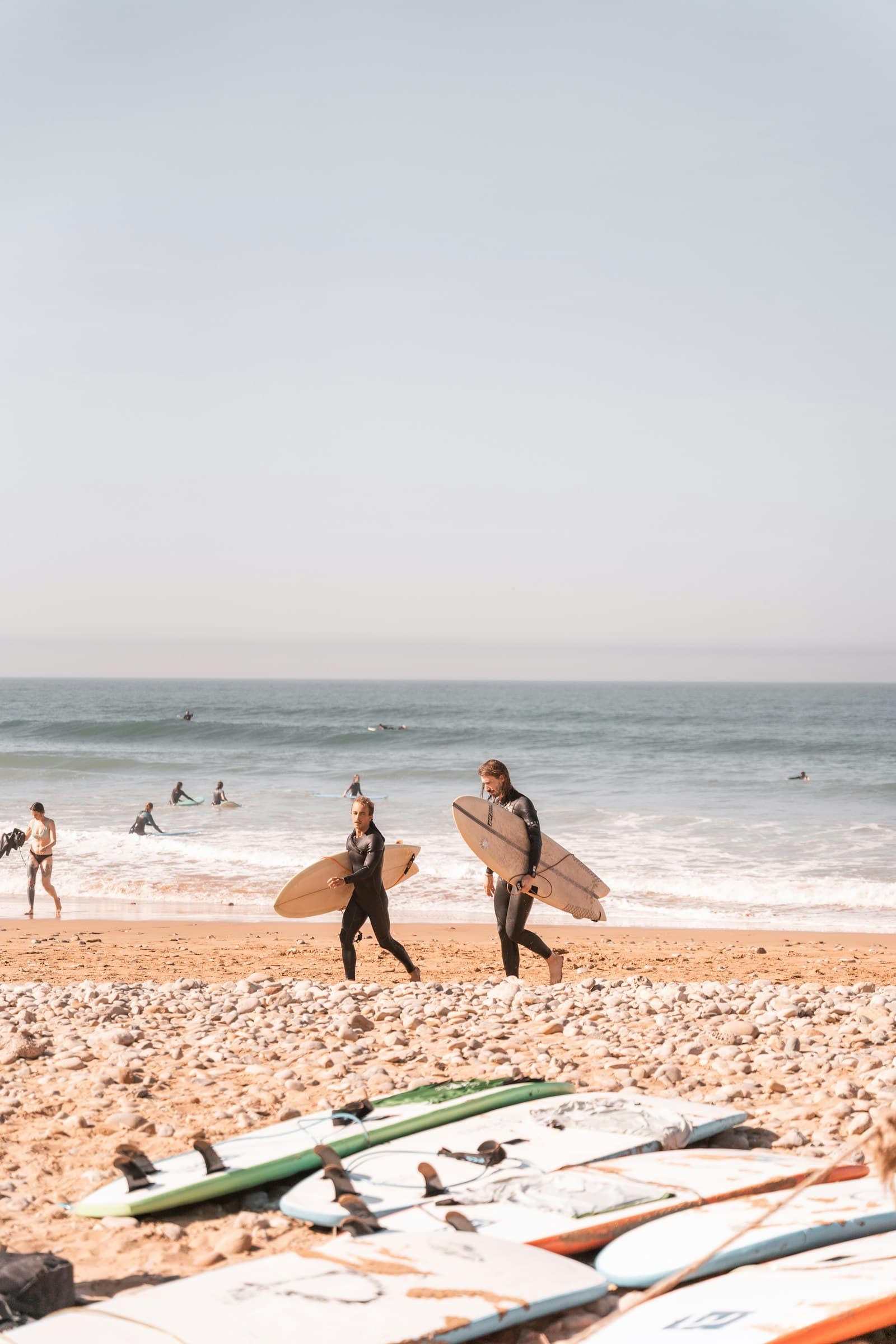 Deux surfeurs marchent sur la plage avec leurs planches
