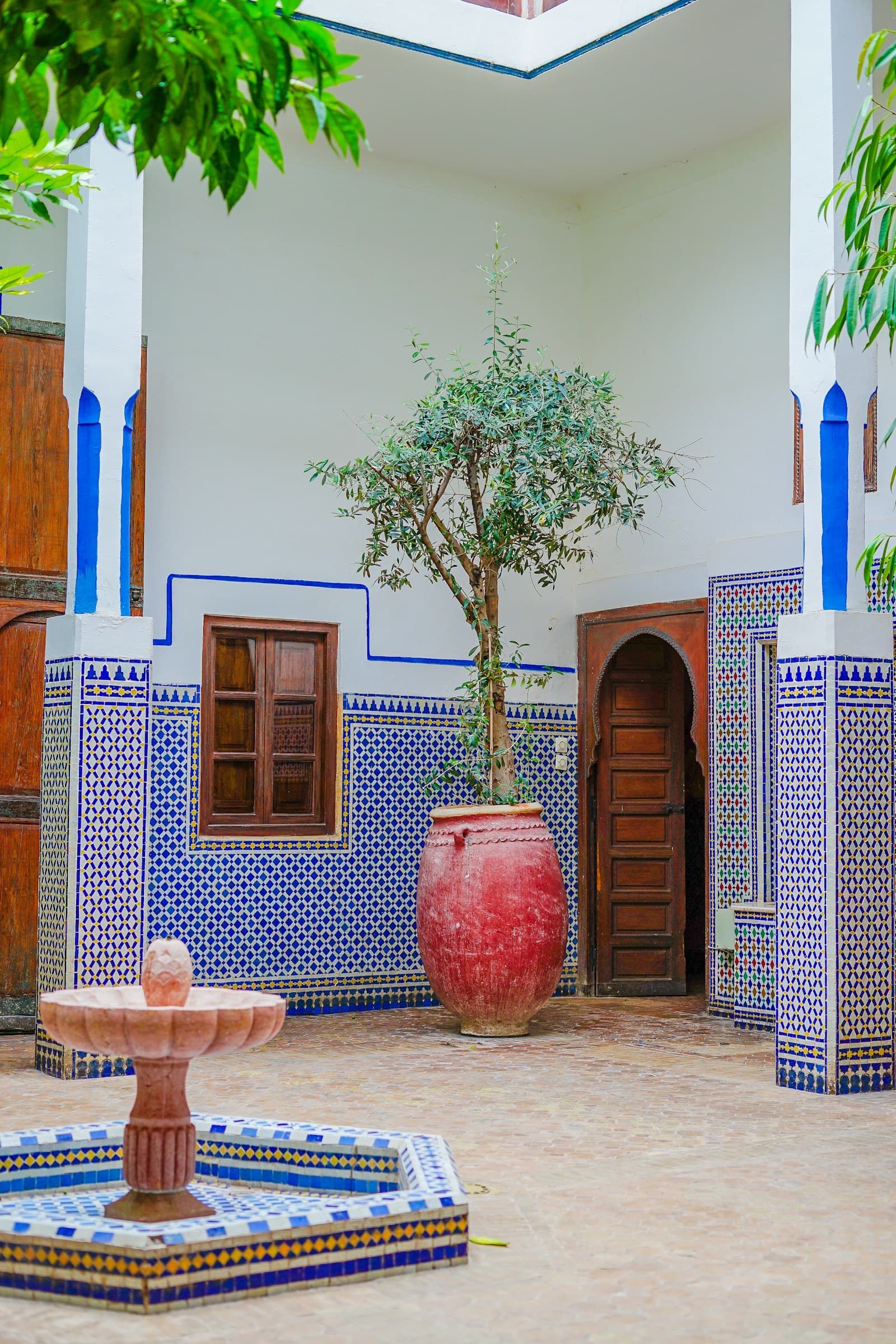 Porte en bois et mur de zellige bleu de l'entrée du riad