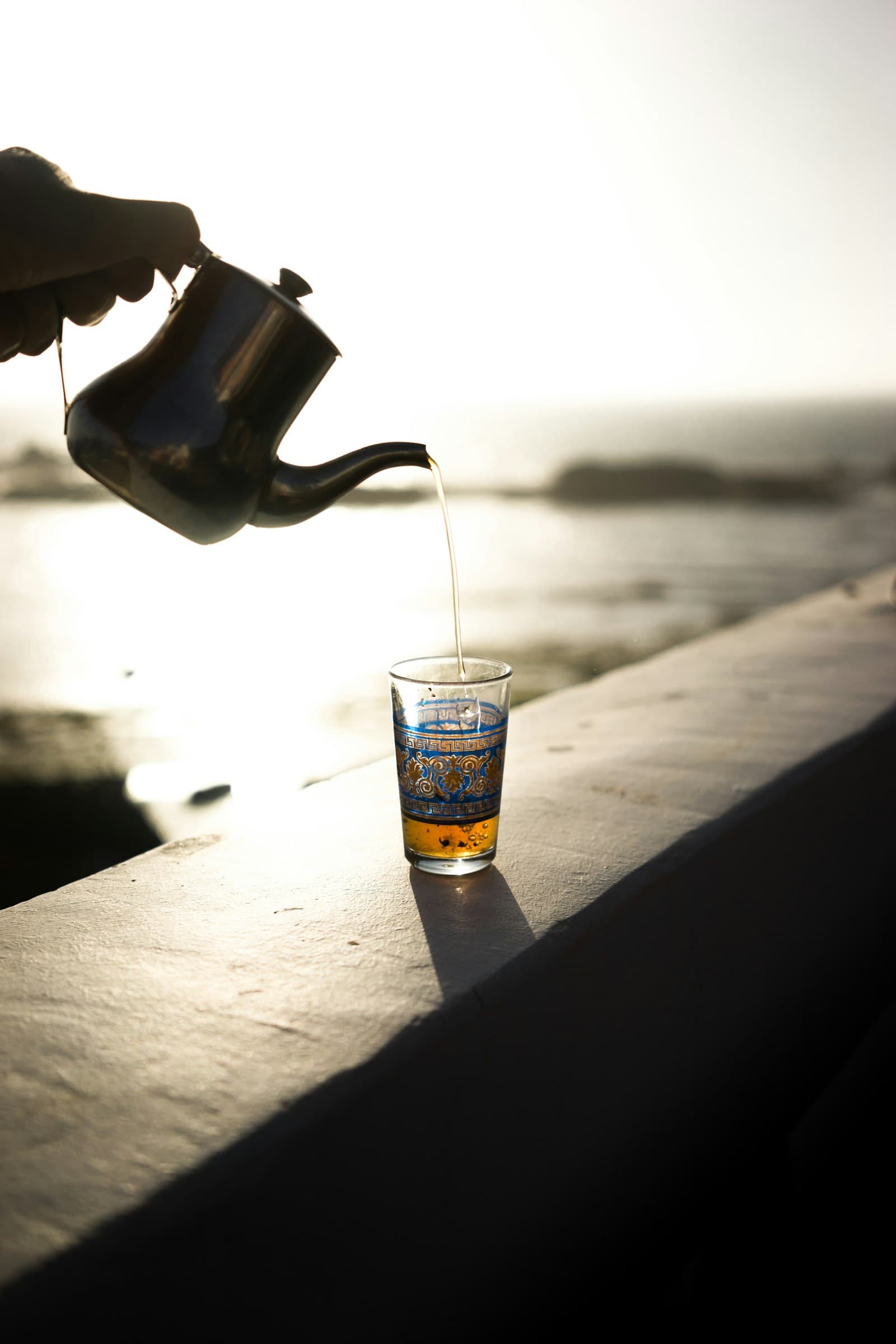 Thé versé de haut dans un verre décoré